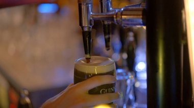 Draw a fresh Guinness beer in a pub - CITY OF DUBLIN, IRELAND - APRIL 20, 2022
