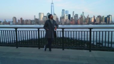 Guy standing at the waterfront in Jersey City and watching the skyline of Manhattan - drone photography