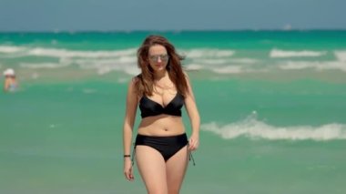 Miami Beach 'te rüzgarlı bir günde bikini giyen güzel bir kız. Ağır çekimde Miami Florida seyahat fotoğrafçılığı. 
