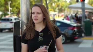 Genç ve güzel bir kadın Miami Sahili 'nin güneşinde soğuk bir şeyler içiyor. Aşırı yavaş çekim videosu.