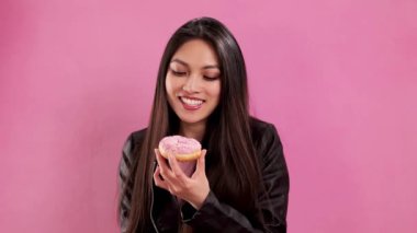 Stüdyoda kendine güveni olan Asyalı bir kız donut yiyor - aşırı yavaş çekim