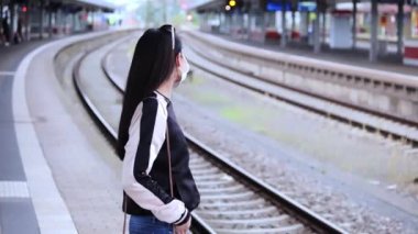 Güzel Asyalı kadın platformda treni bekliyor. İnsanlar fotoğraf çekiyor.