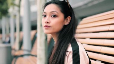 Güzel Asyalı kadın bankta birini bekliyor. Fotoğraf çeken birini.