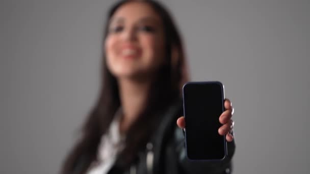 Jonge Vrouw Toont Iets Haar Mobiele Telefoon Studiofotografie — Stockvideo