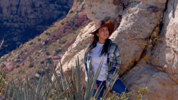 ネバダ州の砂漠の岩の上に座っている西洋スタイルの衣装の若い女性 旅行写真 — ストック動画