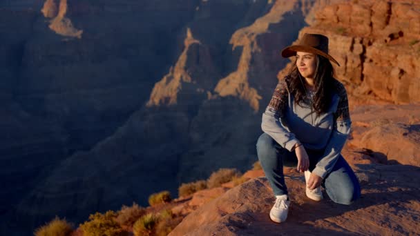 素晴らしいグランドキャニオンに立っているカウボーイハットを着た若いネイティブアメリカンの女性 旅行写真 — ストック動画