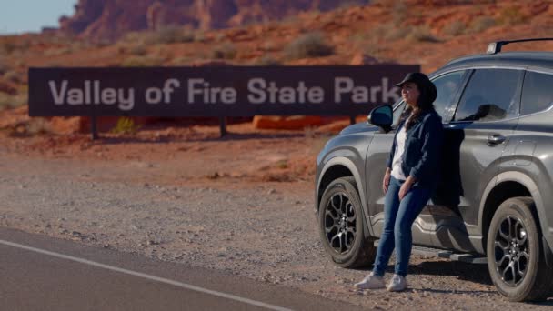 一个年轻的女人靠着她的汽车旅行摄影在沙漠中穿行 — 图库视频影像