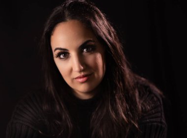 Genç ve güzel bir kadın kameraya gülümsüyor. Stüdyoda manken fotoğrafçılığı.