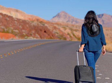 Çölde bavul olarak tek başına yürüyen genç bir kadın. Seyahat fotoğrafçılığı.