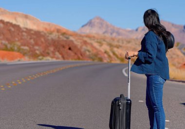 Çölde bavul olarak tek başına yürüyen genç bir kadın. Seyahat fotoğrafçılığı.