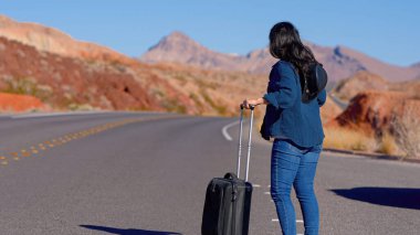 Çölde bavul olarak tek başına yürüyen genç bir kadın. Seyahat fotoğrafçılığı.