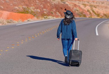 Çölde bavul olarak tek başına yürüyen genç bir kadın. Seyahat fotoğrafçılığı.