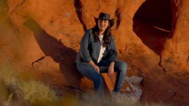 Arizona çölünde kırmızı bir kayanın üzerinde dinlenen kovboy kız - seyahat fotoğrafçılığı