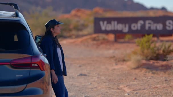 一个年轻的女人靠着她的汽车旅行摄影在沙漠中穿行 — 图库视频影像