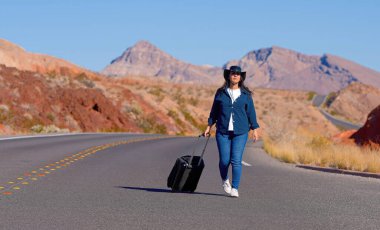 Çölde bavul olarak tek başına yürüyen genç bir kadın. Seyahat fotoğrafçılığı.