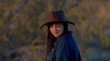 Kameraya poz veren kovboy şapkası takan genç bir kovboy kızın portresi. Seyahat fotoğrafçılığı.