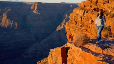 Muhteşem Büyük Kanyon 'un inanılmaz manzarasının tadını çıkaran genç bir kadın. Seyahat fotoğrafçılığı.