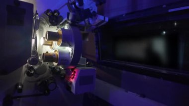 Sinema salonundaki bir sinema projektörünün içinden geçen 35 mm 'lik bir film. Klasik bir sinema projektörü. Sinemada projeksiyon odası