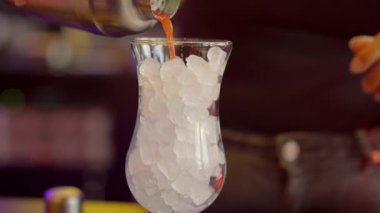 Yetenekli bir barmen bardağa titizlikle buz ekler ve kokteyl hazırlama sürecini ustalıkla gözler önüne serer.