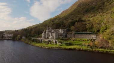 İrlanda 'daki Connemara Ulusal Parkı' ndaki Kylemore Manastırı. Yeşil tepeler içine kurulmuş tarihi bir şatonun havacılık perspektifi. Doğayı ve mimariyi esir alıyor..