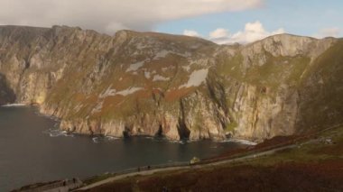 Donegal İrlanda 'daki Slieve Ligi - Avrupa' nın en yüksek kayalıkları - parçalı bulutlu bir gökyüzünün altında sakin okyanusla birleşen engebeli uçurumların nefes kesici manzarasını tecrübe edin.