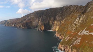 Donegal İrlanda 'daki Slieve Ligi - Avrupa' nın en yüksek kayalıkları - parçalı bulutlu bir gökyüzünün altında sakin okyanusla birleşen engebeli uçurumların nefes kesici manzarasını tecrübe edin.