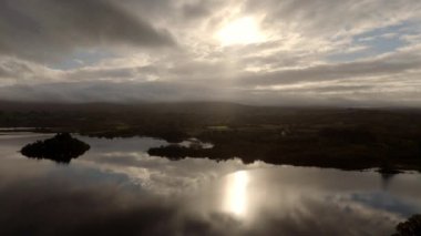 Donegal İrlanda 'da Lough Eske - alacakaranlıkta bulutlu gökyüzünü yansıtan sakin bir göl manzarası, huzuru ve huzuru yansıtıyor