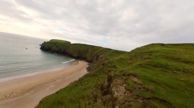 Malin Beg 'deki Donegal' in batı kıyısındaki FPV uçuşu - Resimli ve güzel manzaralı kıyı şeridi bereketli, yeşil tepeler boyunca sakin gök mavisi suları sergiliyor
