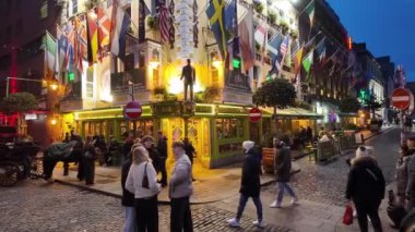 DUBLIN, IRELAND - 12 Ekim 2024 - Dublin Tapınak Bar Bölgesi - hareketli kalabalıklar ve canlı kentsel bir ortamda güzel aydınlatılmış binaların olduğu canlı bir tatil sahnesi