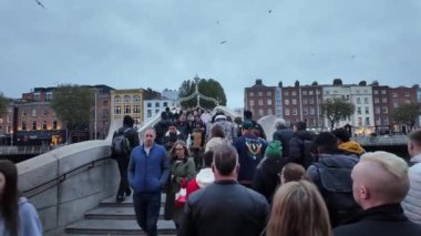 DUBLIN, IRELAND - 12 Ekim 2024 - Hapenny Köprüsü 'nün güzel manzarası bulutlu bir gökyüzünün altındaki sakin nehire yansıyor