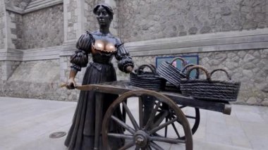 DUBLIN, IRELAND - 12 Ekim 2024 - Dublin İrlanda - Tarihi bir sokak satıcısını temsil eden güzel bir bronz heykel, ahşap bir sepete yerleştirilmiş sepetler