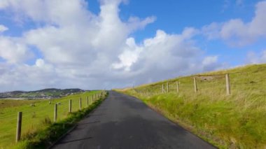 Donegal, İrlanda - Bereketli yeşil tepeler ve bulutlar arasında dingin bir yol esiyor, doğa aşıkları için mükemmel bir doğa güzelliği.