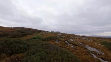 Şaşırtıcı İrlanda - Tipik İrlanda manzarası üzerinde FPV Uçuşu - Sakin bir köy yolu yumuşak bulutlu gökyüzünün altındaki yemyeşil çayırlarda yavaşça kıvrılarak ilerliyor