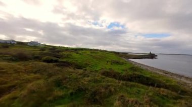 Şaşırtıcı İrlanda - Tipik İrlanda manzarası üzerinde FPV Uçuşu - Sakin bir köy yolu yumuşak bulutlu gökyüzünün altındaki yemyeşil çayırlarda yavaşça kıvrılarak ilerliyor