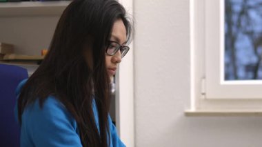 Kendini işine adamış ve profesyonel bir kadın, özenle dizüstü bilgisayarının üzerinde çalışıyor.