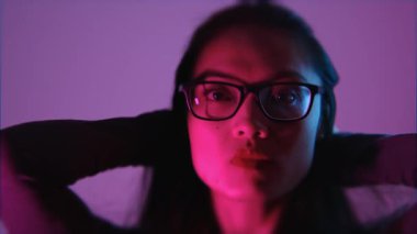 Parlak neon ışıklar ve derin gölgelerin büyüleyici bir karışımı içinde güzel bir Asyalı kadının duygusal ağır çekim portresi. Moda tarzı.