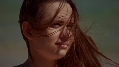Genç bir kadın düşünceli bir şekilde bakıyor, saçları rüzgarda uçuşuyor, sükuneti yakalıyor..
