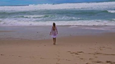 Kumsalda yürüyen bir insanın huzur dolu bir sahnesi. Yakınındaki nazik dalgalarla. Huzur ve sükuneti simgeliyor.