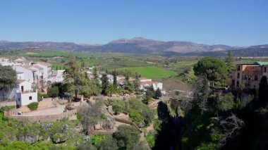 Yeşil vadiye bakan beyaz evler ve Endülüs 'ün güneyindeki Serrania de Ronda dağları ile Ronda şehri.