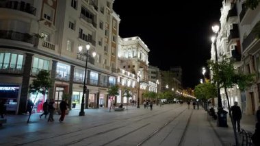 İspanya, Sevilla 'da bir yaya sokağı olan Constitucion Bulvarı' nda insanlar yürüyor, geceleri aydınlatılıyor - SEVILLE, SPAIN - 25 Mart 2025