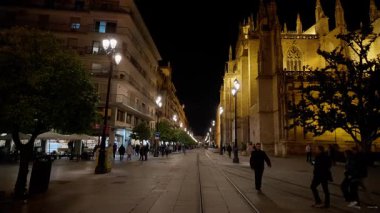 İspanya 'nın Palma de Mallorca kentindeki Seville Katedrali' nin yakınındaki bir sokakta geceleri yürüyen insanlar - SEVILLE, SPAIN - 25 Mart 2025