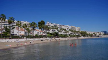 İnsanlar Marbella, İspanya 'da plajda dinlenirken ve denizde yüzerken güneşli bir yaz gününde - MARBELLA, İspanya - 30 Mart 2025