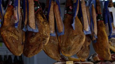 Serrano jambon bacakları geleneksel bir İspanyol pazarında kancalardan sarkıyordu, satışa hazırdı - CADIZ, SPAIN - 27 Mart 2025