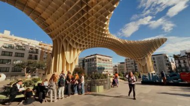 İspanya 'nın Sevilla kentindeki Metropol Şemsiyesi' nin gölgesinde yürüyen ve dinlenen turistler güneşli bir günde - SEVILLE, SPAIN - 25 Mart 2025
