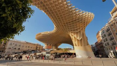 Plaza de la Encarnacion 'da büyük ahşap bir yapı olan Metropol Şemsiyesi altında Sevilla' da yürüyen turistler - SEVILLE, SPAIN - 25 Mart 2025