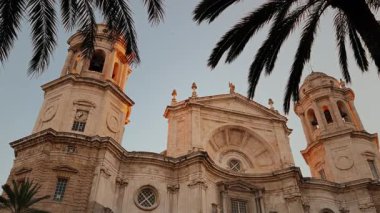 Cadiz Katedrali, karamsar bir gökyüzüne karşı dimdik duruyor, palmiye ağaçları tarafından çerçevelenmiş.