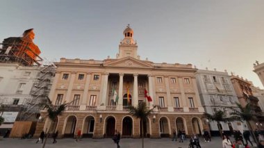 Günbatımında San Juan de Dios Meydanı 'nda Cadiz Belediye Binası önünde yürüyen turistler, Endülüs, İspanya - CADIZ, İspanya - 26 Mart 2025