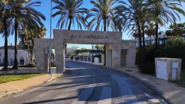 İspanya 'nın Marbella şehrinde, Marbella şehrinde, Efsane Marbella' nın taş girişi ve mavi gökyüzü altında palmiye ağaçları - MARBELLA, İspanya - 30 Mart 2025