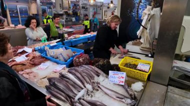 Müşteriler Cadiz, İspanya 'daki bir pazardan deniz ürünleri alırken balıkçı taze balık hazırlıyor - CADIZ, SPAIN - 26 Mart 2025