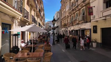İnsanlar Cadiz, İspanya 'da yürürken ve güneşli bir günün tadını çıkarırken, restoranlar ve barlarla - CADIZ, SPAIN - 26 Mart 2025